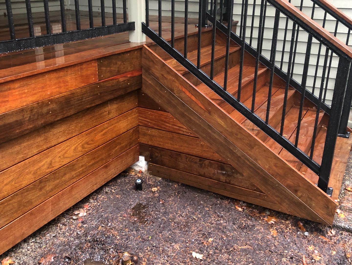 Finished exterior stairway with stained wood treads and a black metal railing