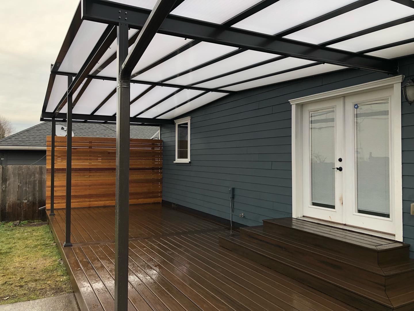 A finished covered patio with a polycarbonate roof over a wood deck
