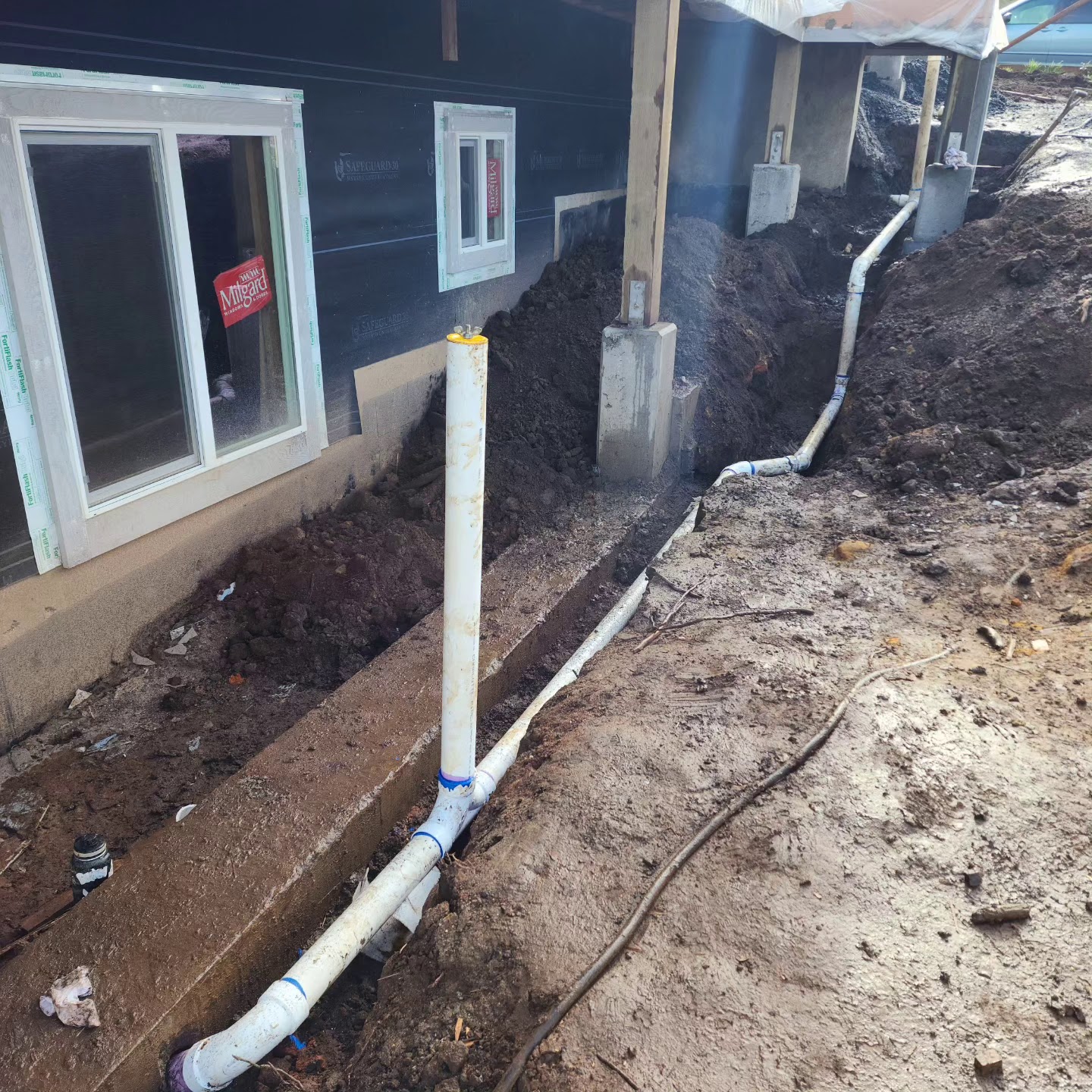Drainage and plumbing rough-in work along a foundation