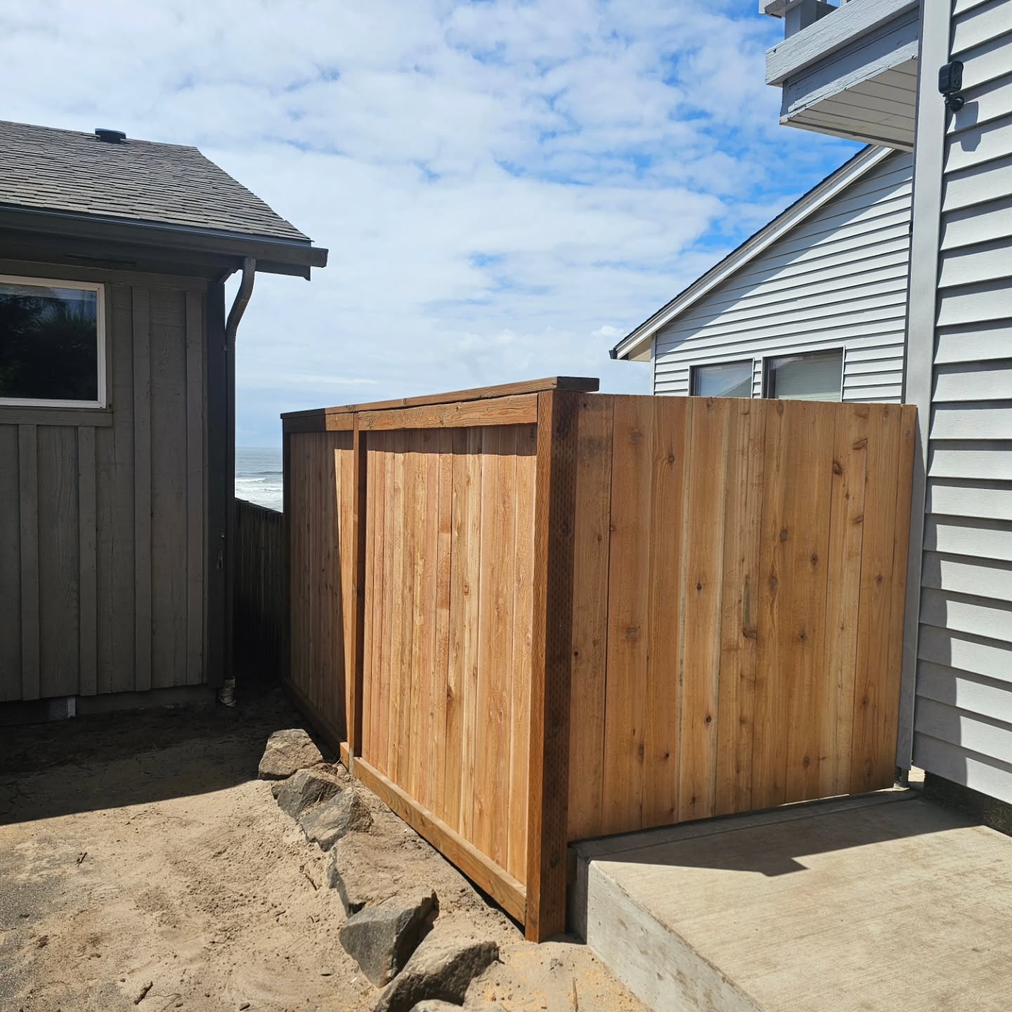 A new cedar fence built beside a home with an ocean view