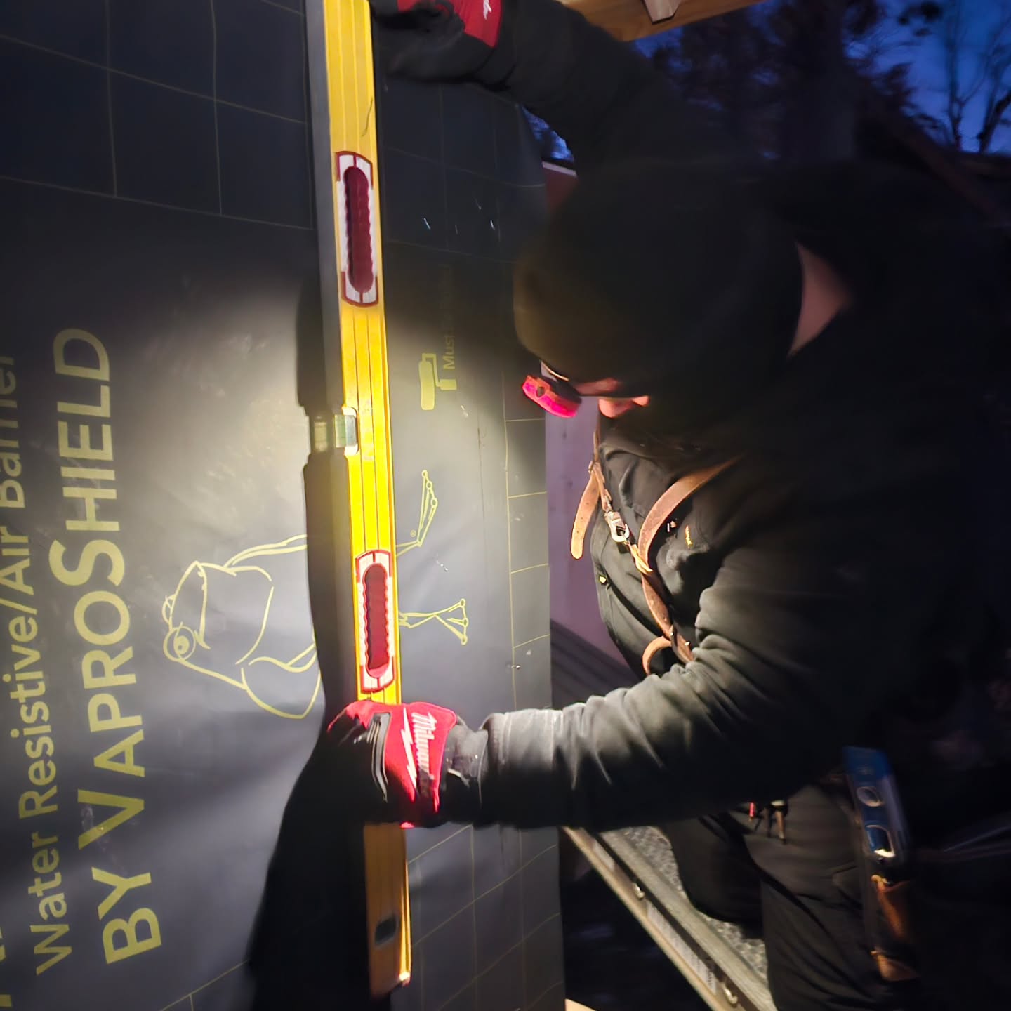 Crew installing a weather-resistive barrier on wall framing
